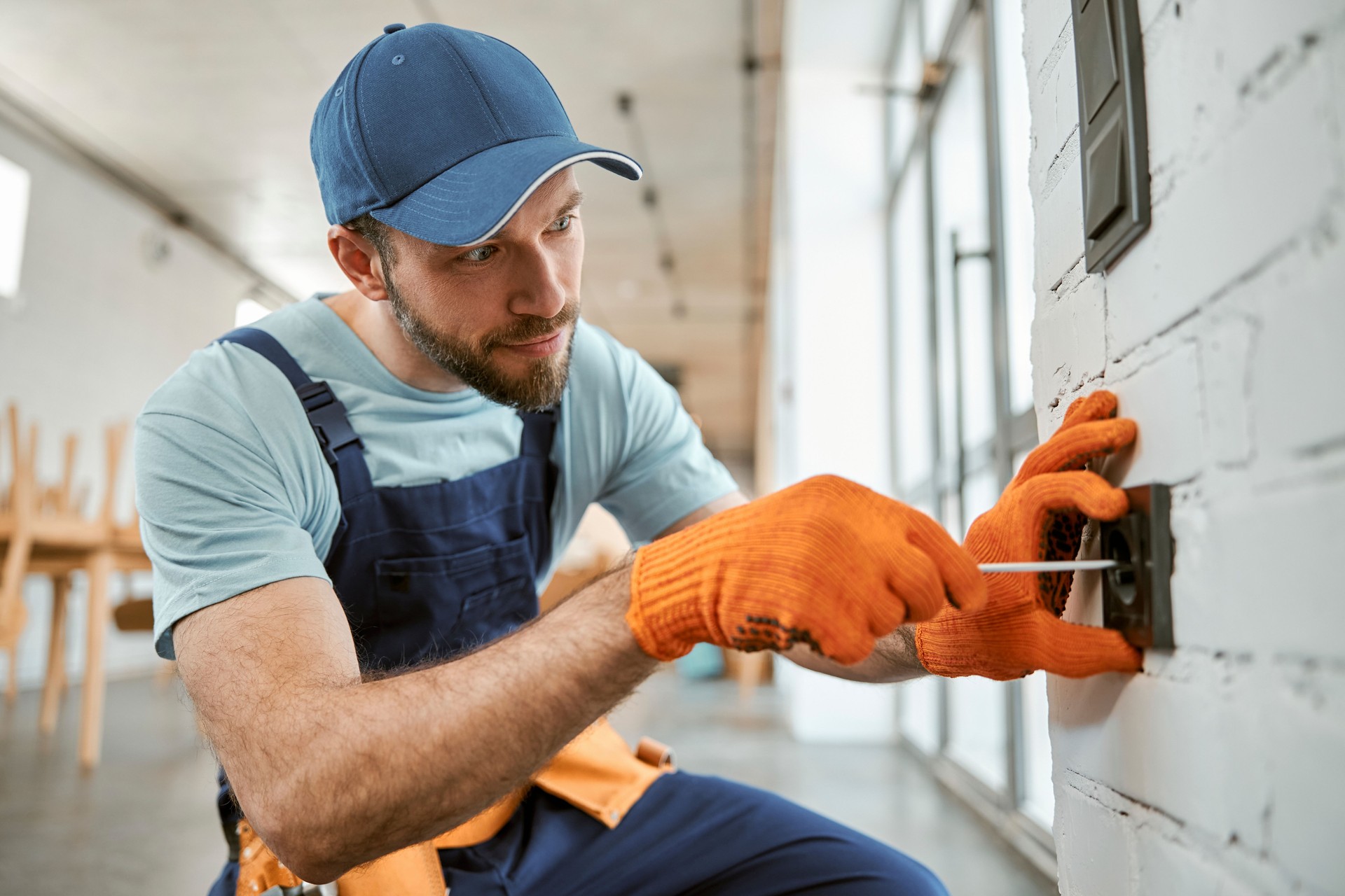 Bearded man fixing electrical wall socket with screwdriver