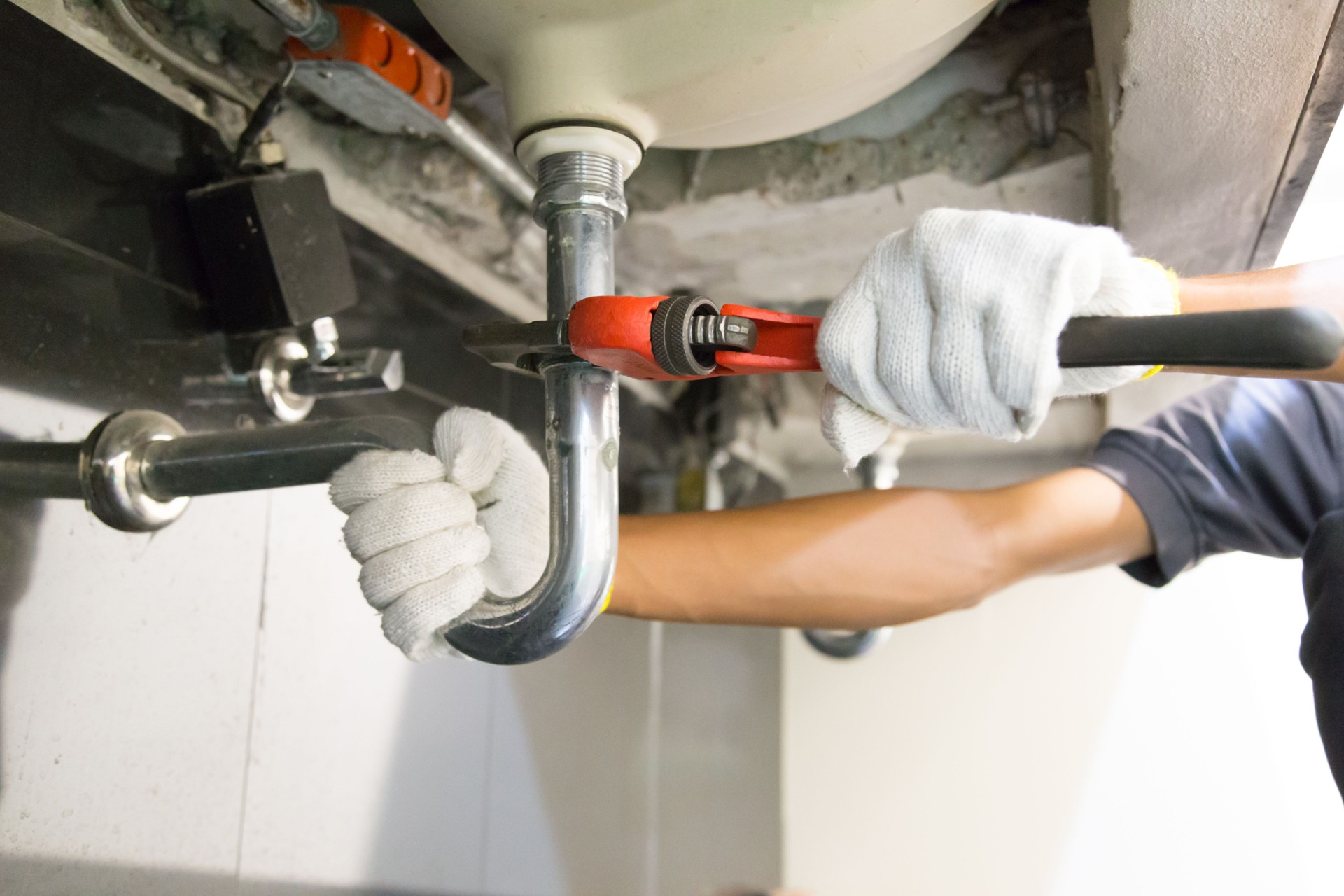 Cropped Hands Of Plumber Repairing Pipe